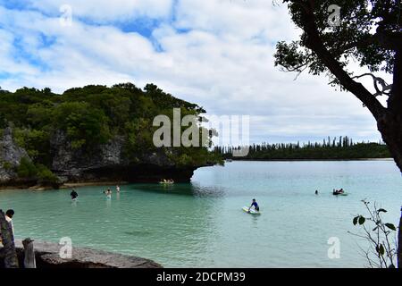 The sacred rock, Rocher de Kaa Nuë Méra in Kanumera Bay on Isle of Pines, New Caledonia. Tourist swim in the blue waters and play on paddle boards. Stock Photo