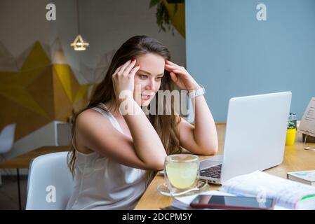Pensive thoughtful concentrated businesswoman looking at laptop screen while working on her laptop at cafe, coworking. Remote work concept. Freelancer Stock Photo