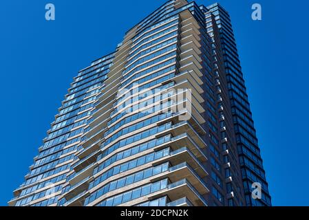 Brooklyn, NY - November 14 2020: The top of a new residential skyscraper in Greenpoint, NYC, silhouetted against a blue cloudless sky. The building is Stock Photo