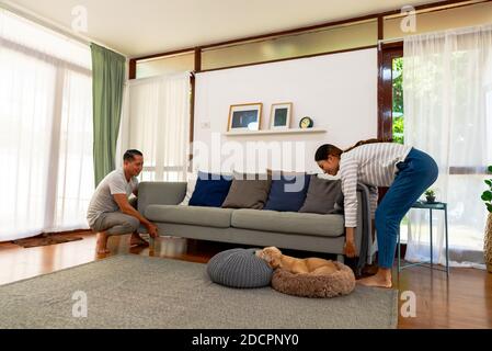 Young couple carrying a modern sofa chair together. Millennial family moving new furniture into new home. Furnishing and renovating new house concept Stock Photo