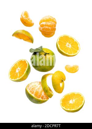 Fresh ripe green mandarine with leaf falling in air. Cut, peeled, slices and whole green tangerine isolated on white background with clipping path. Food levitation concept Stock Photo