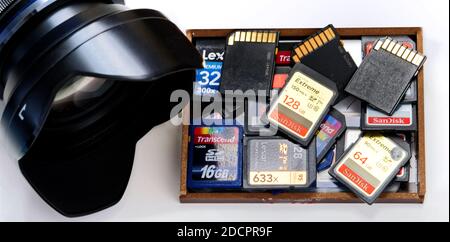 Box with SD memory cards with different sizes and manufacturers beside a camera lens Stock Photo