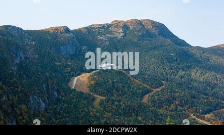 Mt. Mansfield - view of cliff outcrops, the ridge, and the summit. Gondola upper terminal and ski slopes through a mixed forest. Stowe, Vermont, USA. Stock Photo