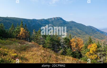 Mt. Mansfield - cliff outcrops, the ridge, and the summit. Mixed forest with trees changing color in the fall. Lodge and ski trails. Stowe, VT, USA. Stock Photo