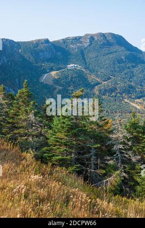 Mt. Mansfield - cliff outcrops, the ridge, and the summit. Mixed forest with trees changing color in the fall. Lodge and ski trails. Stowe, VT, USA. Stock Photo