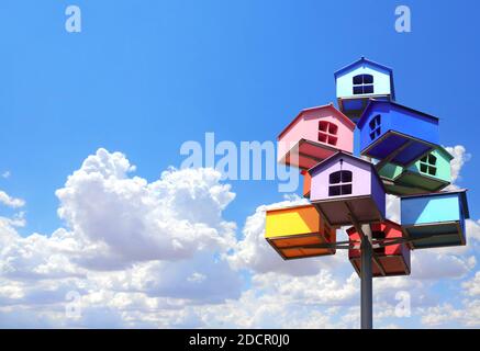 Colorful nesting boxes on blue sky background. Many birdhouses of different colors and blue sky with clouds Stock Photo