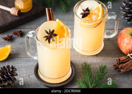 Seasonal winter or Christmas hot spicy drink, mulled cider. Hot rum, whiskey or brandy apple toddy cocktail drinks on rustic wooden table. Stock Photo