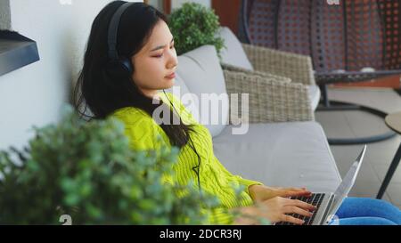 Young asian woman, freelancer , working on her laptop with headset. Distance learning or remote work concept. High quality photo Stock Photo