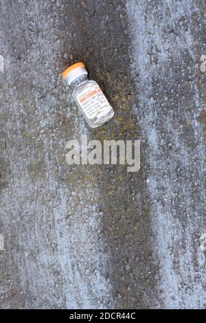 Empty Naloxone HCL vial left on the ground; opioid antagonist used for the treatment of known or suspected opioid overdose; opioid effect blocker. Stock Photo