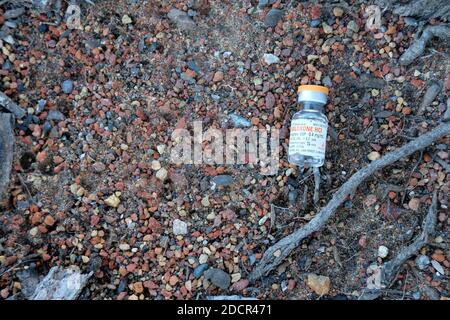 Empty Naloxone HCL vial left on the ground; opioid antagonist used for the treatment of known or suspected opioid overdose; opioid effect blocker. Stock Photo