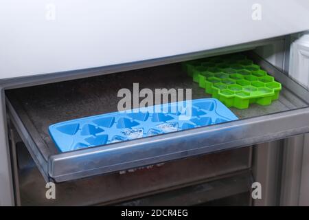 A man takes ice from a freezer tray to freeze low food in one layer. Stock Photo