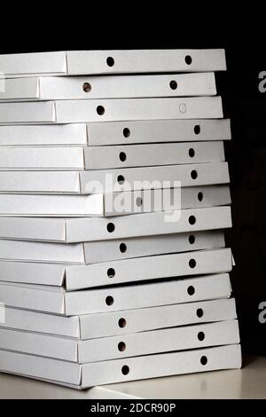 Stack of white closed cardboard pizza boxes on dark background Stock Photo