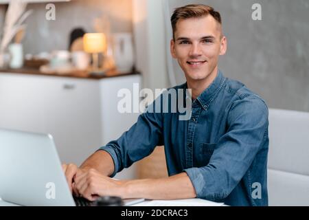 male freelancer works on a laptop in his kitchen. Stock Photo
