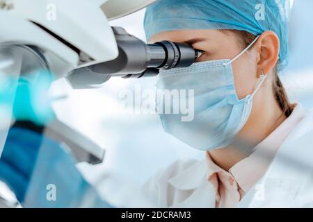 female scientist using a microscope in a medical laboratory. Stock Photo