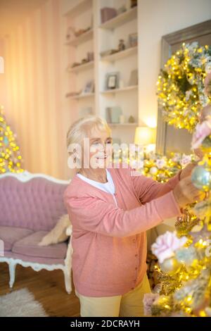 Elderly woman looking busy while decorating christmas tree Stock Photo