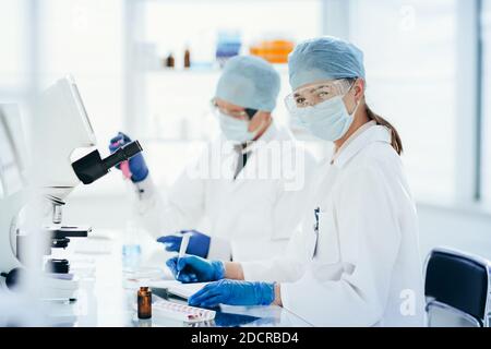 scientists testing the liquid and writing the results in a laboratory journal. Stock Photo