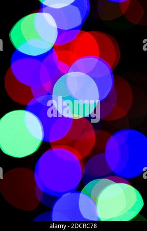 Blurry colored lights of garlands. A vertical arrangement of a beautiful Christmas and New Year background. Copy space. Stock Photo