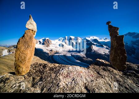 Two rock cairns on a rock, the summits of Piz Palü, Bella Vista and Piz Bernina and the upper part of Pers Glacier, seen from Munt Pers near Diavolezz Stock Photo