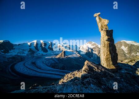 A rock cairn on a rock, the summits of Piz Palü, Bella Vista and Piz Bernina and the upper part of Pers Glacier, seen from Munt Pers near Diavolezza a Stock Photo