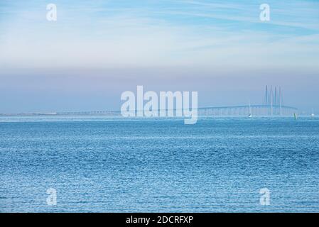 Amid the fog or mist, the Oresund Bridge or Oresundsbron lies on a calm Baltic sea as commuters cross the Oresund strait between Denmark and Sweden Stock Photo