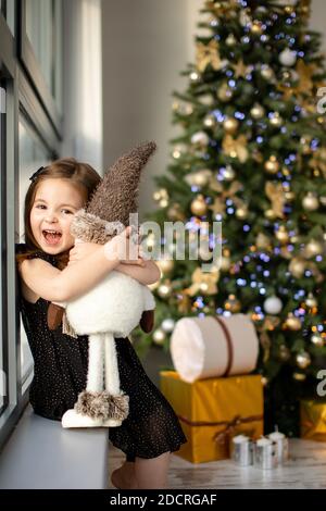 Cute small girl with snowman having fun near Christmas tree indoor. Merry Christmas and Happy New Year Stock Photo