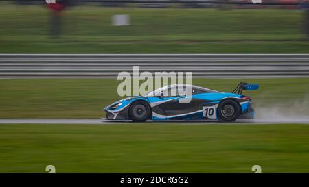 A panning shot of a racing car as it circuits a track. Stock Photo