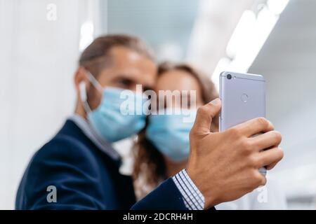 young couple in protective masks taking selfies in subway. Stock Photo