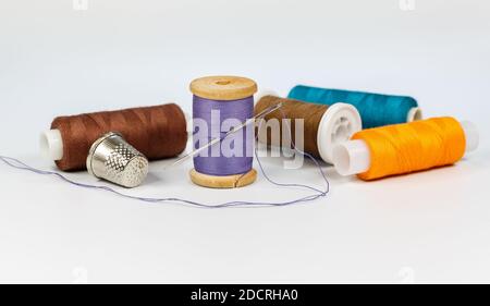 Multicolored thread, needle and thimble on a white background closeup Stock Photo