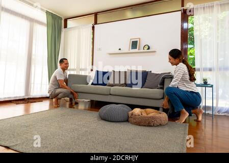 Young couple carrying a modern sofa chair together. Millennial family moving new furniture into new home. Furnishing and renovating new house concept Stock Photo