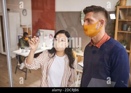 High angle portrait of two modern business people writing on glass panel while planning project in office, copy space Stock Photo
