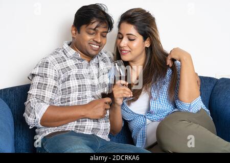 Couple relaxing on sofa with glasses of wine in new home Stock Photo