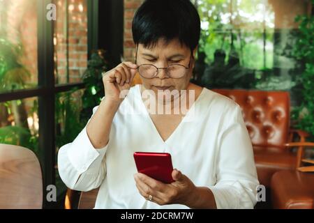 Senior woman wearing  glasses and lookning at smartphone Stock Photo