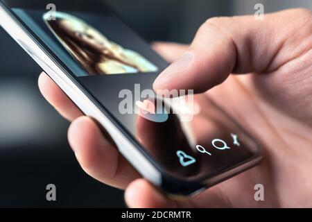 Online dating app in mobile phone. Like or swipe to match. Single man looking for love and relationship with smartphone. Woman with beautiful profile. Stock Photo