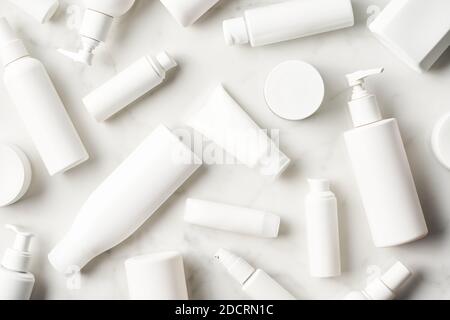 Top view of blank bottles and tubes with skin care products arranged on white marble background Stock Photo