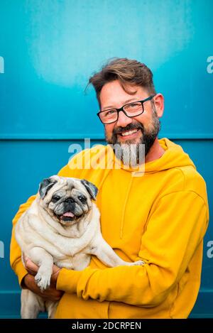 Best friend together forever concept with handsome cheerful adult man and his adorable puppy old pug dog portrait - people and animals love concept fo Stock Photo