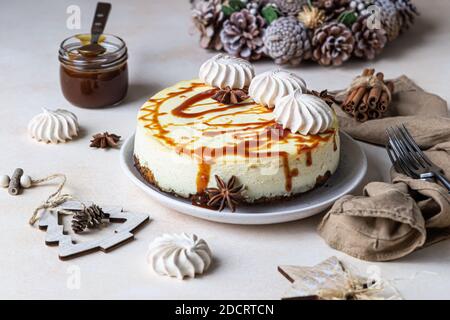 Vanilla cheesecake with carrot cake crust served with salty caramel topping and meringue, light concrete background. Selective focus. Stock Photo