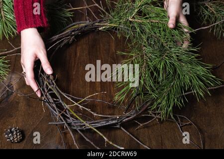 Woman making christmas wreath from nature branches. Wooden dark table Stock Photo