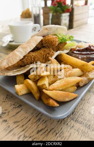 Skin on Fries with southern fried chicken strips in pitta bread Stock Photo