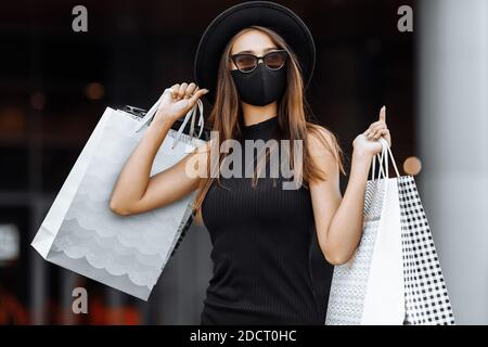 Beautiful young girl shopaholic in medical face mask and