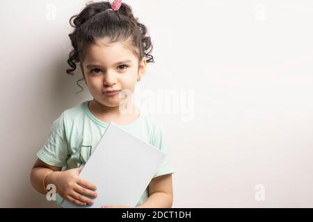 Little girl holding a children book with blank cover in front of body, editable mock-up series template ready for your design, cover selection path in Stock Photo