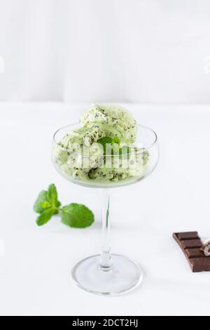 Scoops of mint ice cream with chocolate crumbs in a glass over white background. Summer refreshing dessert. Stock Photo