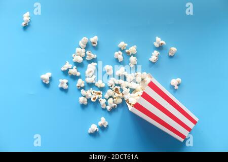 popcorn spilling from a container on blue background  Stock Photo