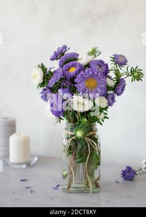beautiful bouquet of lilac and white flowers in a glass vase on a light background Stock Photo