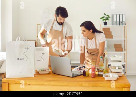 Employees of a restaurant form an order for an online delivery service and pack it in packages. Stock Photo