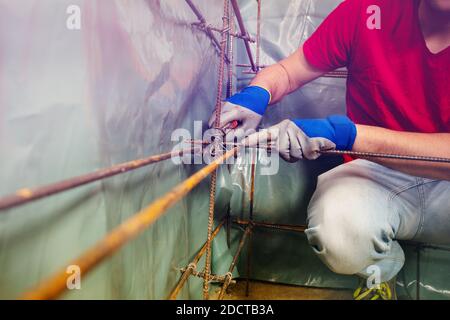 Closeup of a man hands knit metal rods framework with bars and wiring using pliers Stock Photo