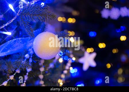 White ball hanging on a Christmas tree, Christmas ornaments at night, blue and gold holiday lights Stock Photo
