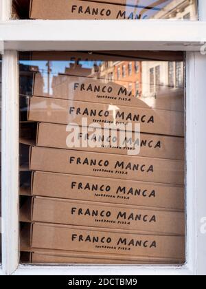 Cardboard pizza boxes stacked in a window of a Franco Manca sourdough pizza restaurant Stock Photo