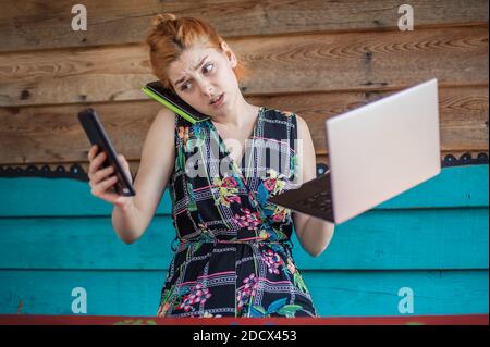 Young crazy hipster talking on the mobile smart phone, using tablet and looking on laptop. Internet connection, networking. Device electronics gadget Stock Photo