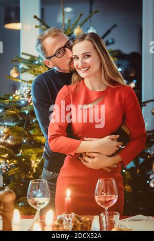 Middle aged couple in romantic pose in front of Christmas tree Stock Photo