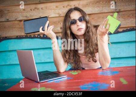 Young crazy hipster talking on the mobile smart phone, using tablet and looking on laptop. Internet connection, networking. Device electronics gadget Stock Photo